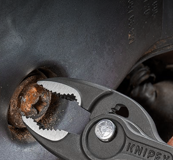 The powerful serrated front jaws of the KNIPEX TwinGrip removing a stripped bolt from a flat surface.